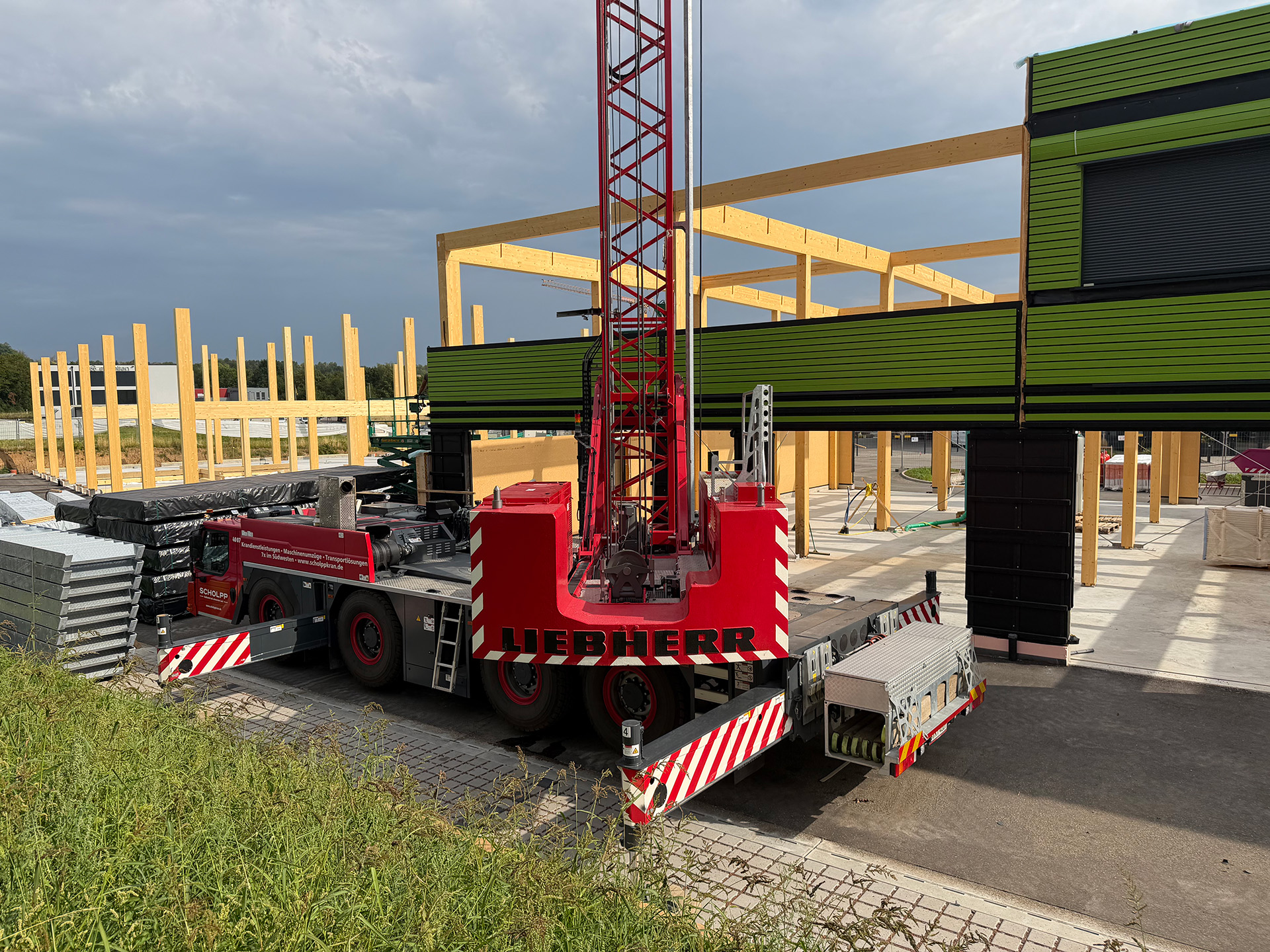 Mobilkran vor dem Brettschichtholz-Tragwerk während der Montage