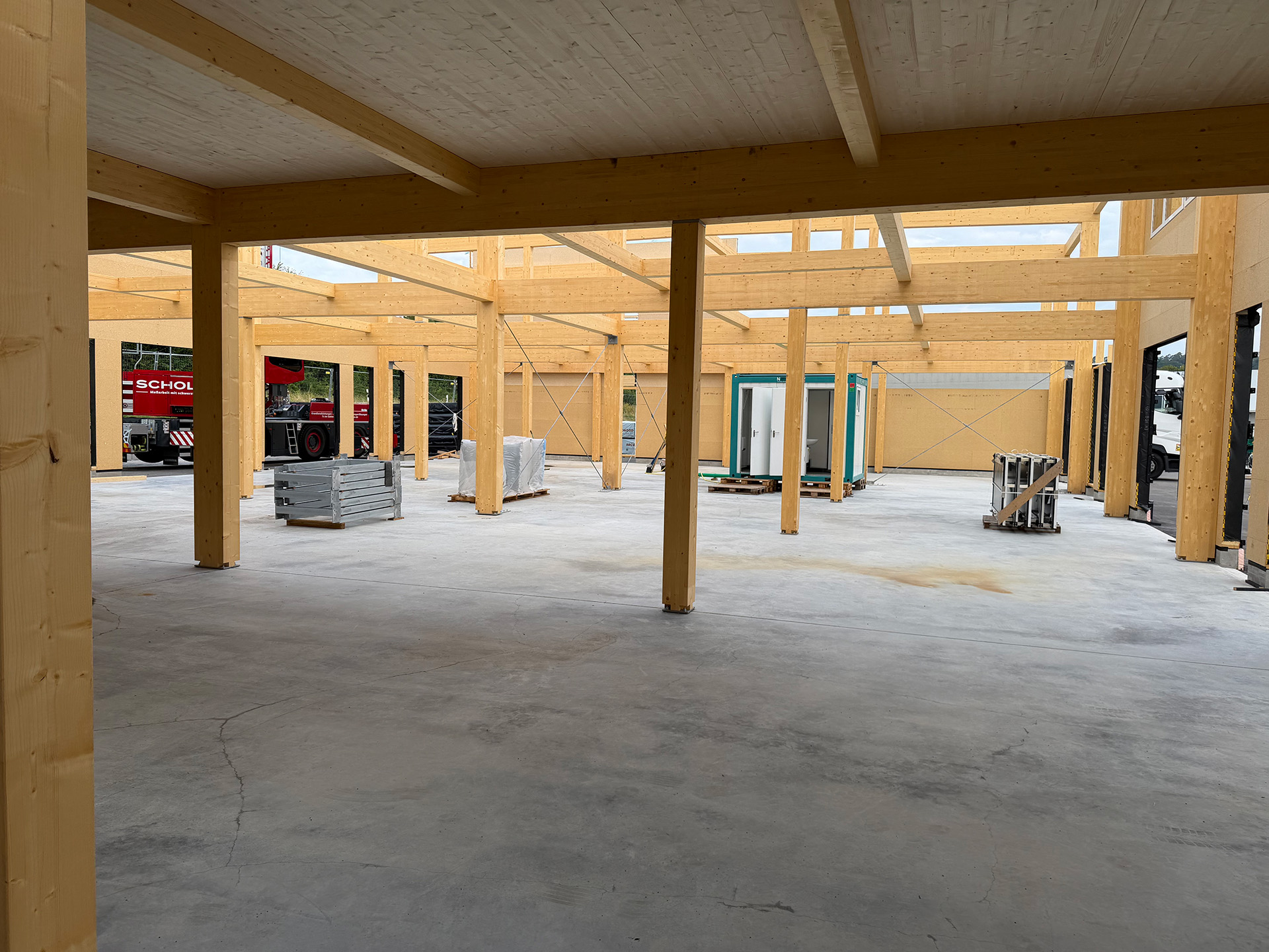 Sichtbare Brettschichtholzstützen und Deckenelemente im Innenraum der fertigen Halle